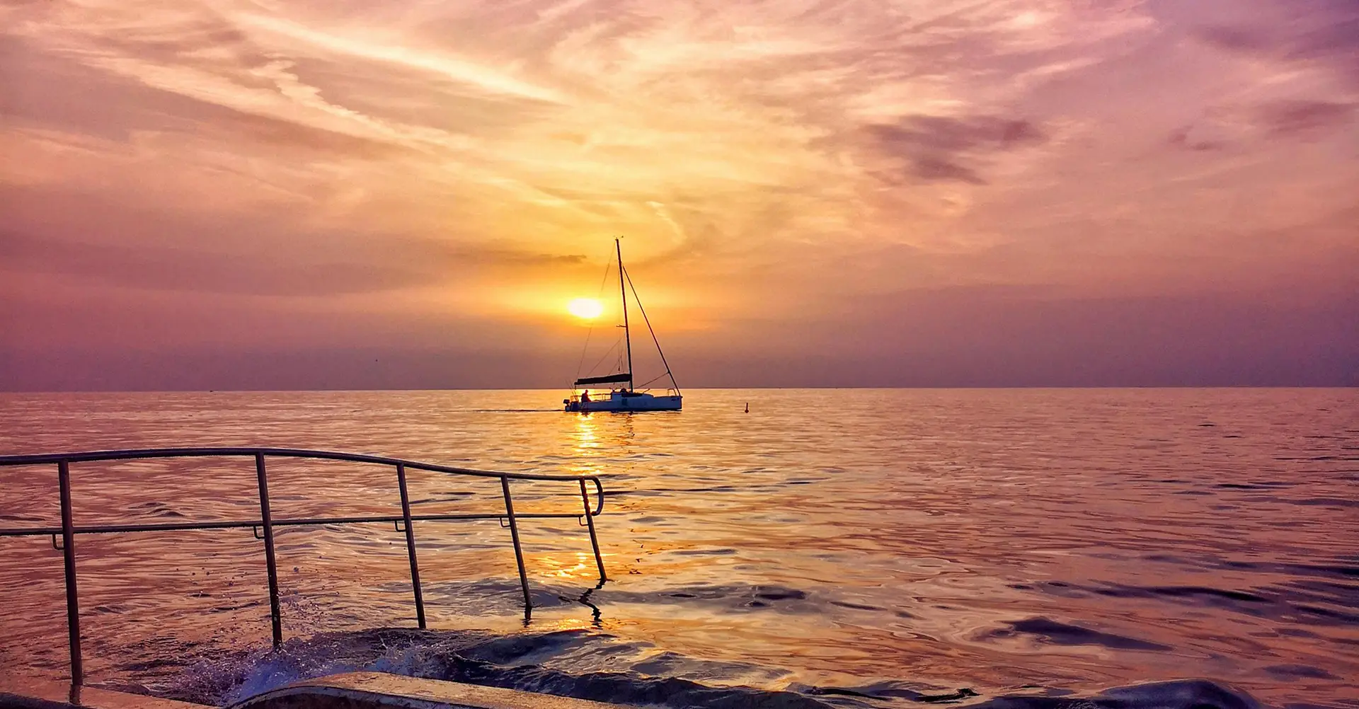 Ein Segelboot bei Sonnenuntergang und ruhiger See vor dem Avcon Yacht Büro in Portorož