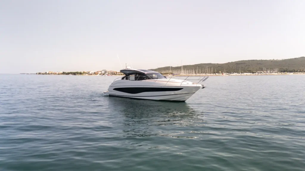 Die Princess V50 – Decksalon seitlich aufgenommen nahe eines Hafens, mit Segelmasten und Uferbebauung im Hintergrund.