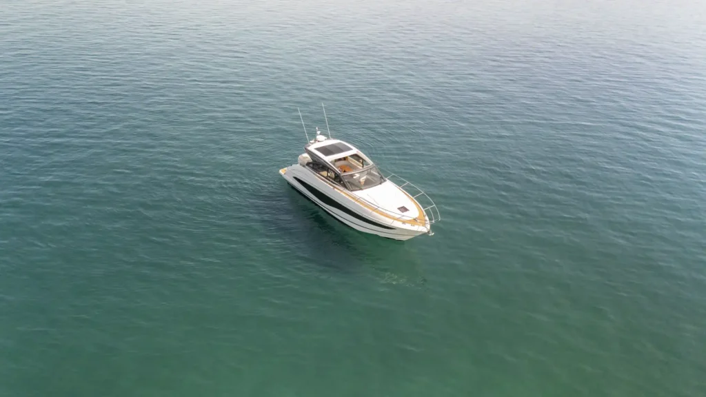 Hohe Draufsicht auf die Princess V50 – Decksalon, ruhig treibend im klaren Wasser, mit Fokus auf Rumpf und Aufbau.