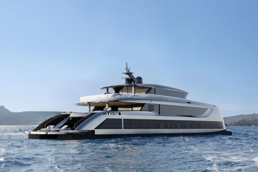 Eine Sunreef Yacht, die bei Tageslicht durch das Meer fährt, mit einer felsigen Küste im Hintergrund. Das schlanke, moderne Design des Schiffes betont seine aerodynamischen Linien und die großzügigen Decksflächen.