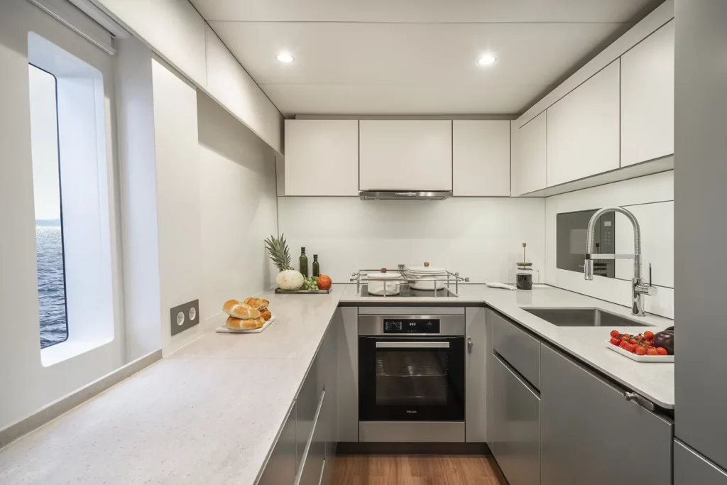 Moderne, elegante Küche auf der Sunreef 60, mit Edelstahlgeräten, minimalistischem Design und einem Panoramafenster mit Blick auf den Ozean.