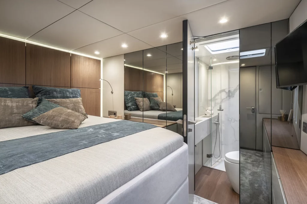 Luxuriöses Schlafzimmer auf der Sunreef 60, mit einem geräumigen Bett, sanfter Beleuchtung und großen Fenstern, die einen malerischen Blick auf das Meer bieten.