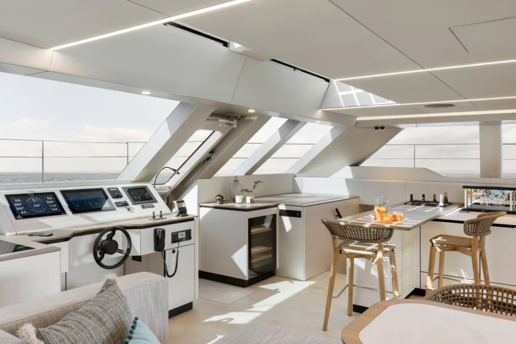 Der Steuerstand der Sunreef Power 60P Eco Yacht, integriert in den offenen Wohnbereich. Moderne Instrumente und ein Panoramablick auf das Meer betonen die innovative und luxuriöse Ausstattung der Yacht.