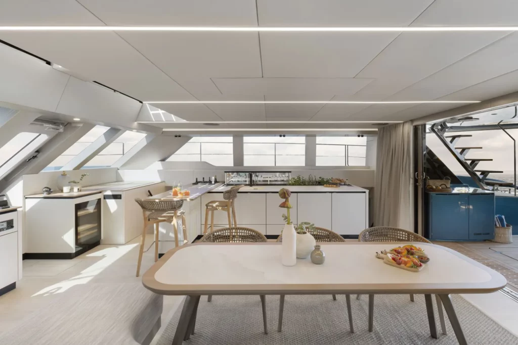 Der offene Küchen- und Essbereich der Sunreef Power 60P Eco Yacht, mit moderner Ausstattung und eleganten Möbeln. Große Fenster und ein minimalistisches Design schaffen eine helle und einladende Atmosphäre.