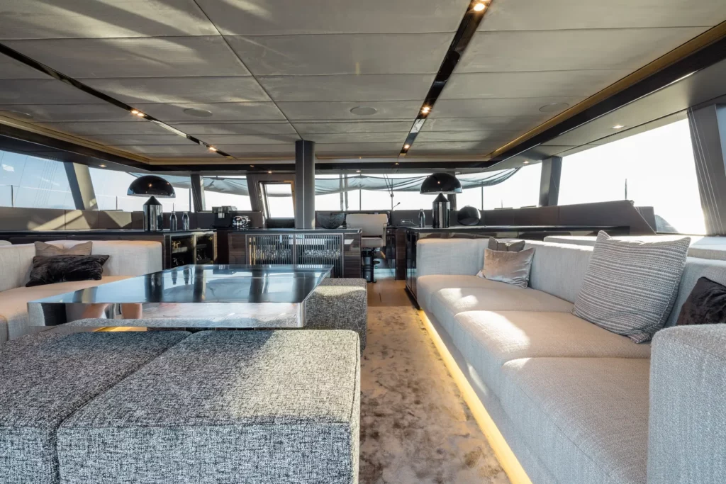 Großer Wohnbereich im Innenraum der Sunreef 70, ausgestattet mit zwei langen Sofas, einem modernen Couchtisch und warmen Lichtakzenten, die den Raum gemütlich machen.