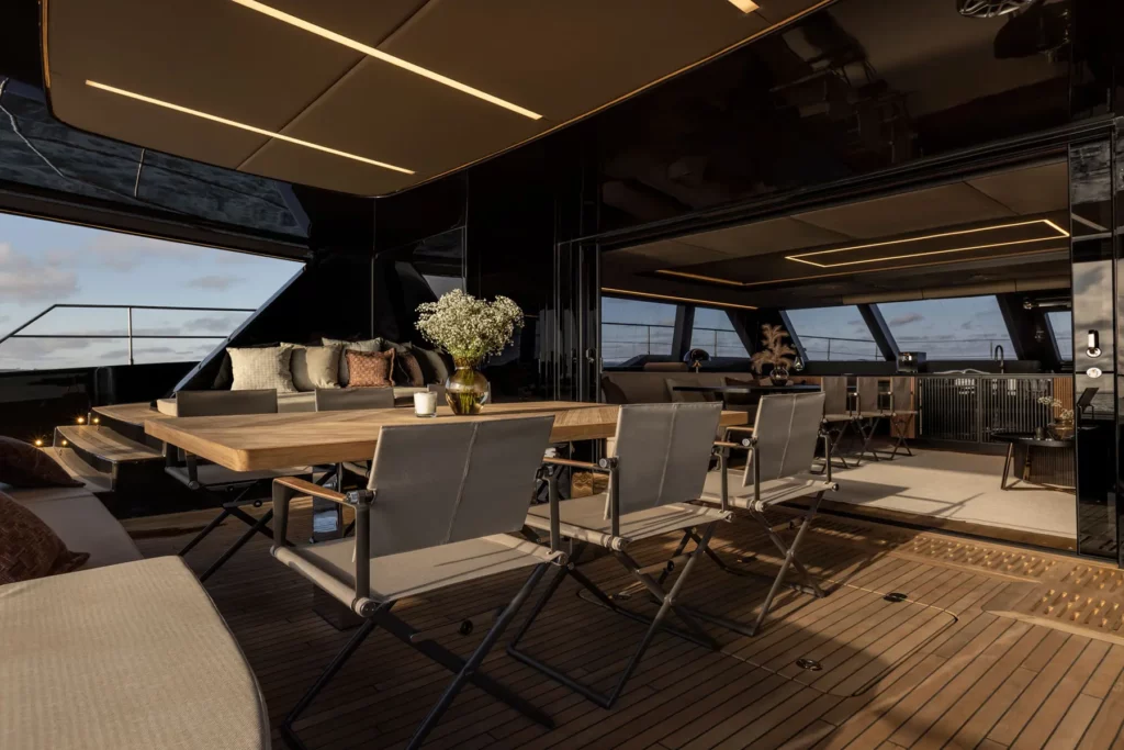 Der luxuriöse Salon des 70 Sunreef Power mit einer großen Couch, stilvollen Lampen und Panoramafenstern, die einen beeindruckenden Blick auf das Meer bieten.