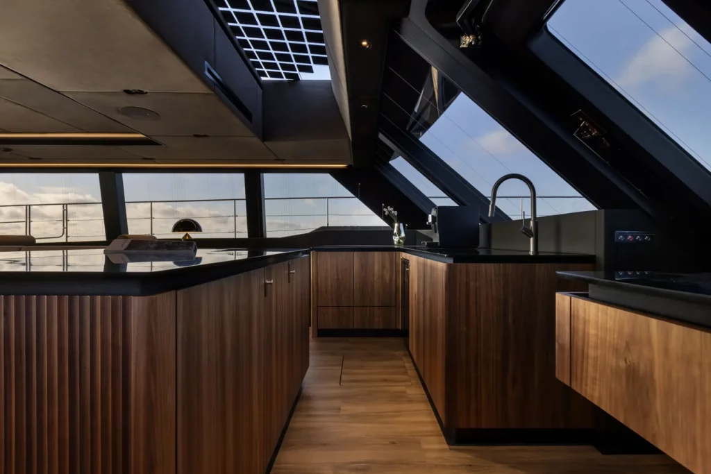 Die moderne Küche des 70 Sunreef Power, mit hochwertigen Holzoberflächen und einem minimalistischen Design, beleuchtet durch ein großes Deckfenster.
