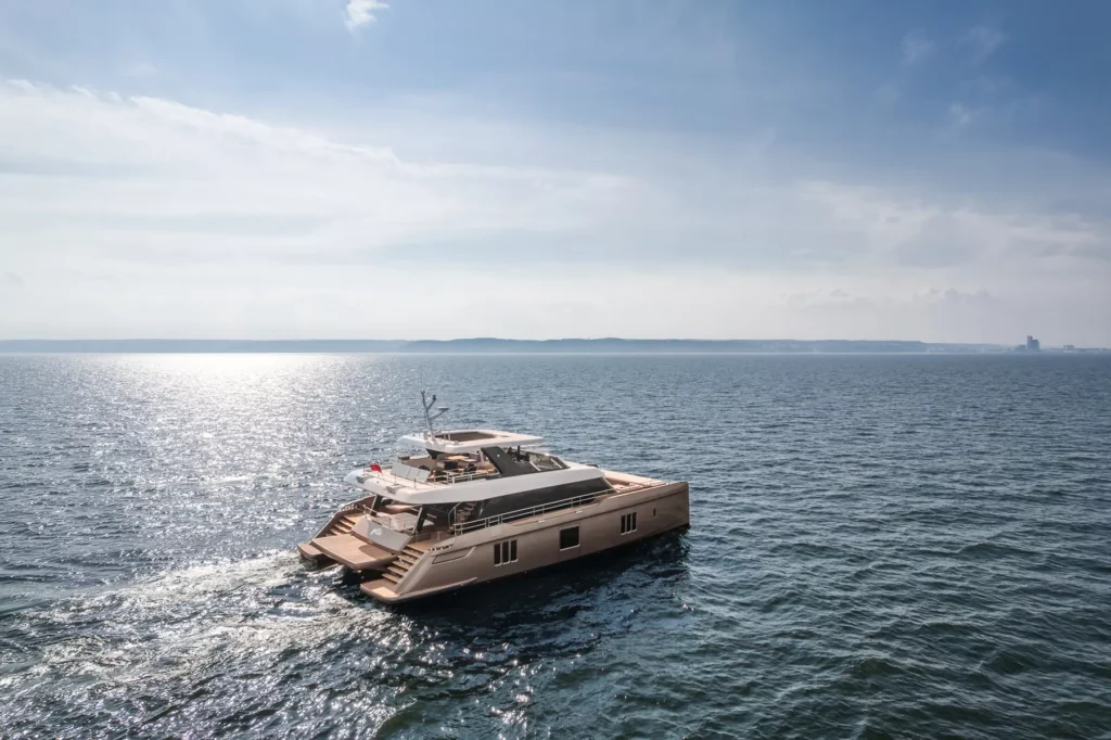 Die 80 Sunreef Power Yacht gleitet elegant über das offene Meer, ihre stilvolle Silhouette und das glatte Deck sind in der Weite des Wassers zu sehen.
