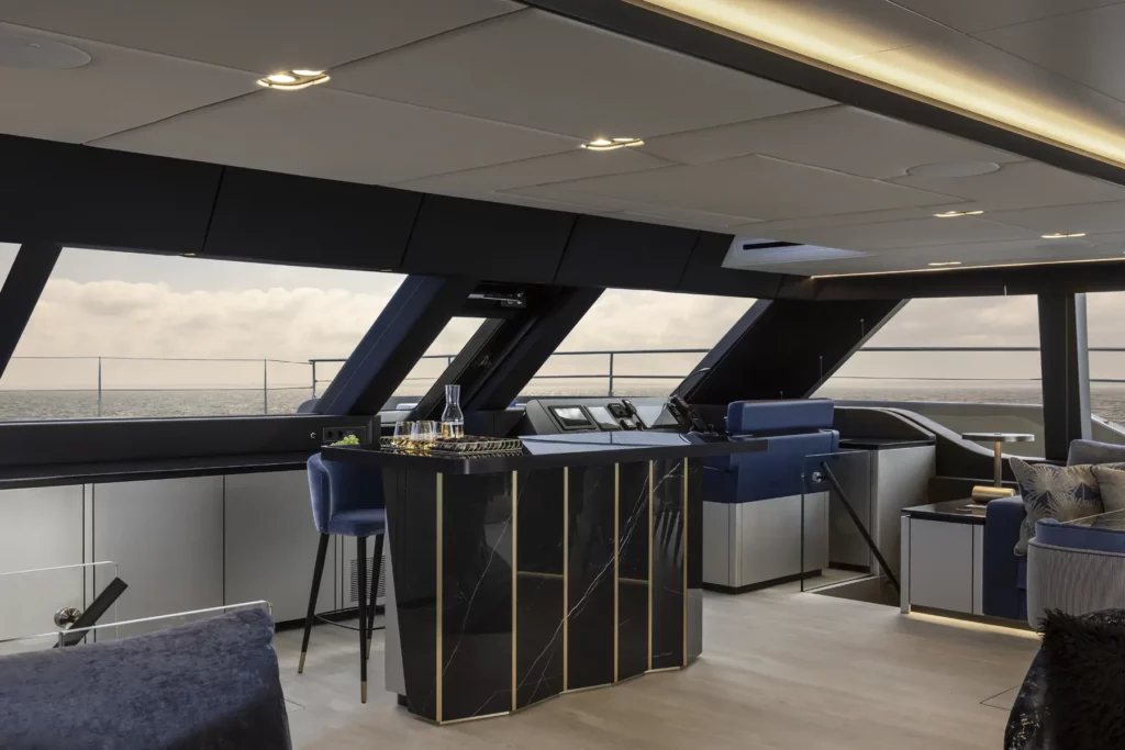 Ein Weitwinkelblick aus dem Lounge-Bereich der 80 Sunreef Power Yacht, der das luxuriöse Interieur mit komfortablen Sitz- und Essbereichen zeigt, alle eingerahmt von großen Fenstern, die einen atemberaubenden Meerblick bieten.