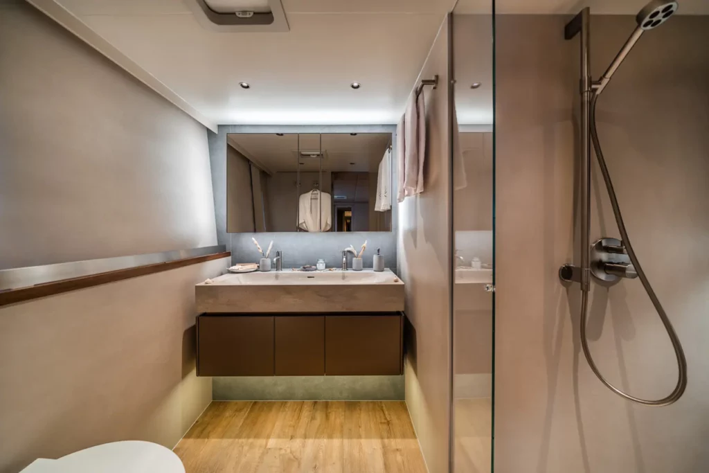 Modernes Badezimmer auf dem Sunreef 80 Katamaran, ausgestattet mit Doppelwaschbecken, Glasdusche und stilvollem, neutralem Design.