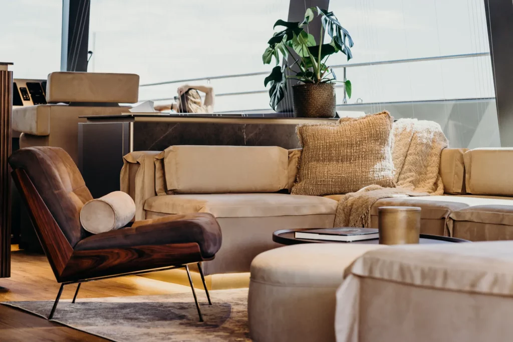 Detailansicht eines komfortablen Sitzbereichs im Salon des Sunreef 80 Katamarans, mit einem weichen Sessel, Kissen und einem dekorativen Pflanzenarrangement.