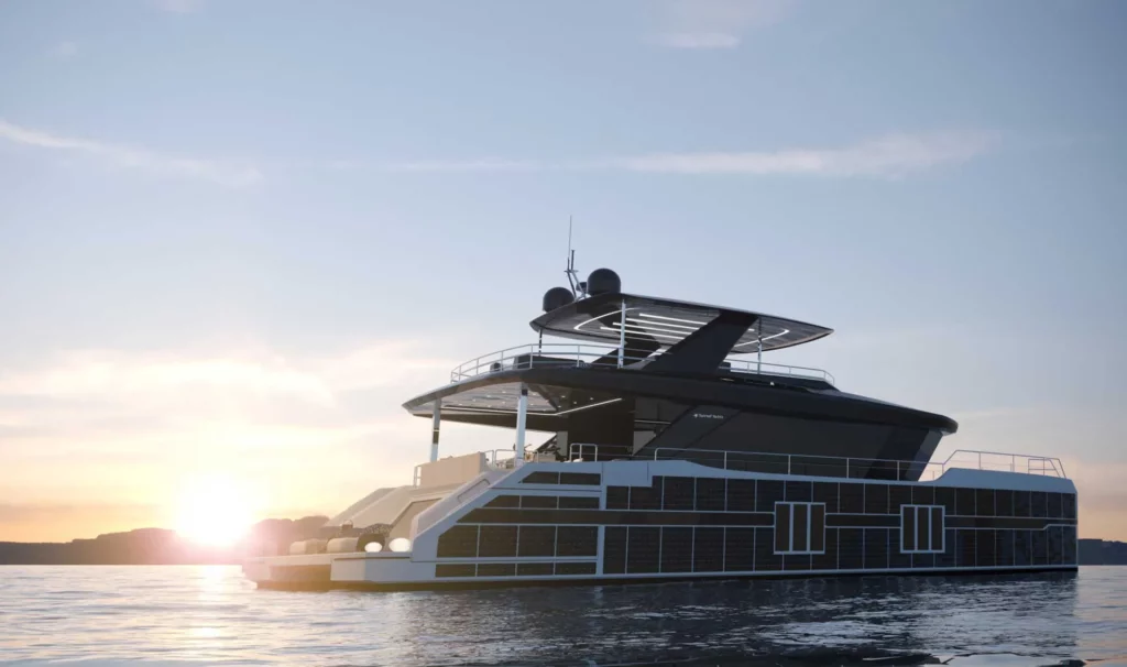 Abendstimmung auf einem Sunreef Supreme Power Eco-Katamaran, der im Wasser vor einem Sonnenuntergang liegt, die Seiten des Bootes sind mit Solarzellen verkleidet.