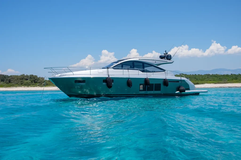 Die Fairline Targa 48 Open gleitet ruhig über das Wasser mit einer grünen Küste und Bergen im Hintergrund.