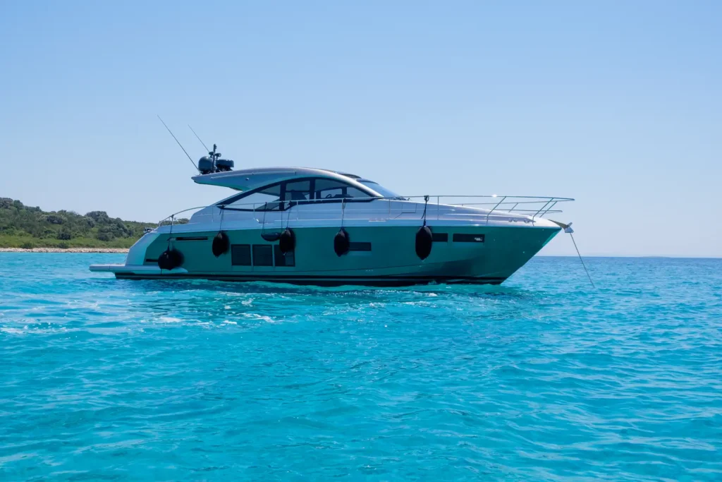 Die Fairline Targa 48 Open aus seitlicher Perspektive im kristallklaren Meer bei sonnigem Wetter.