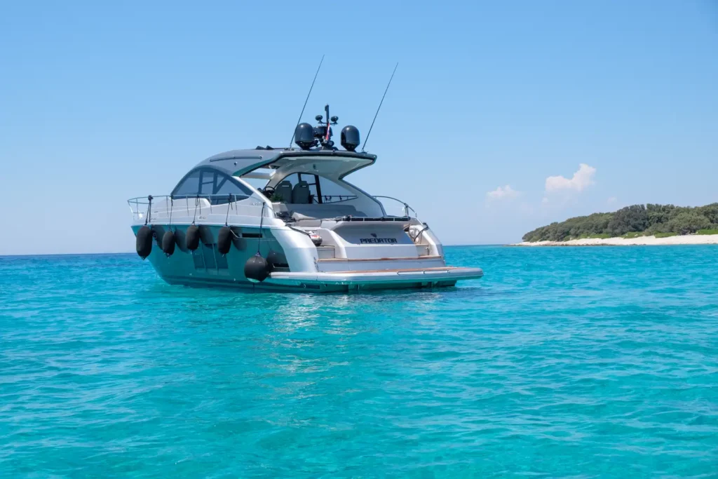Rückansicht der Fairline Targa 48 Open mit geöffneter Badeplattform, die ins türkisfarbene Wasser führt.