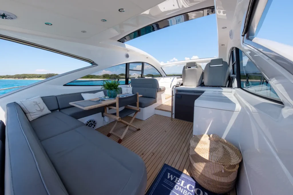Innenraum der Fairline Targa 48 Open mit stilvollem Sitzbereich, gedecktem Tisch und Blick aufs Meer.