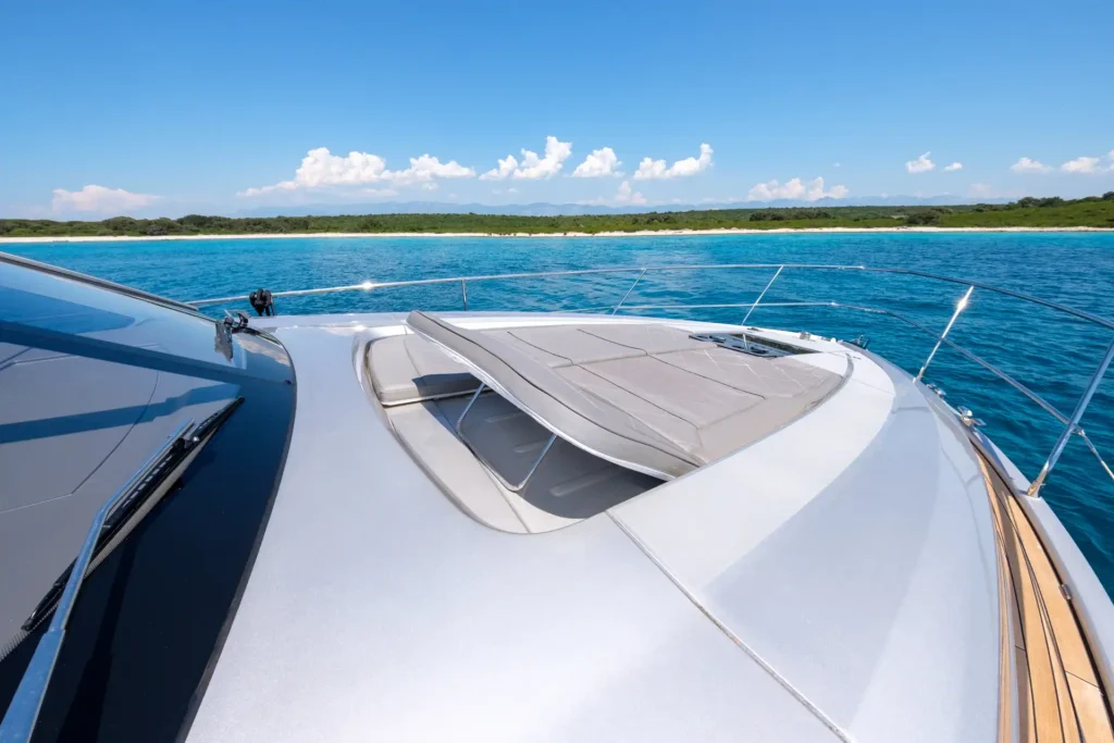 Hochklappbare Sonnenliege auf dem Vorschiff der Fairline Targa 48 Open, umgeben von blauem Meer.
