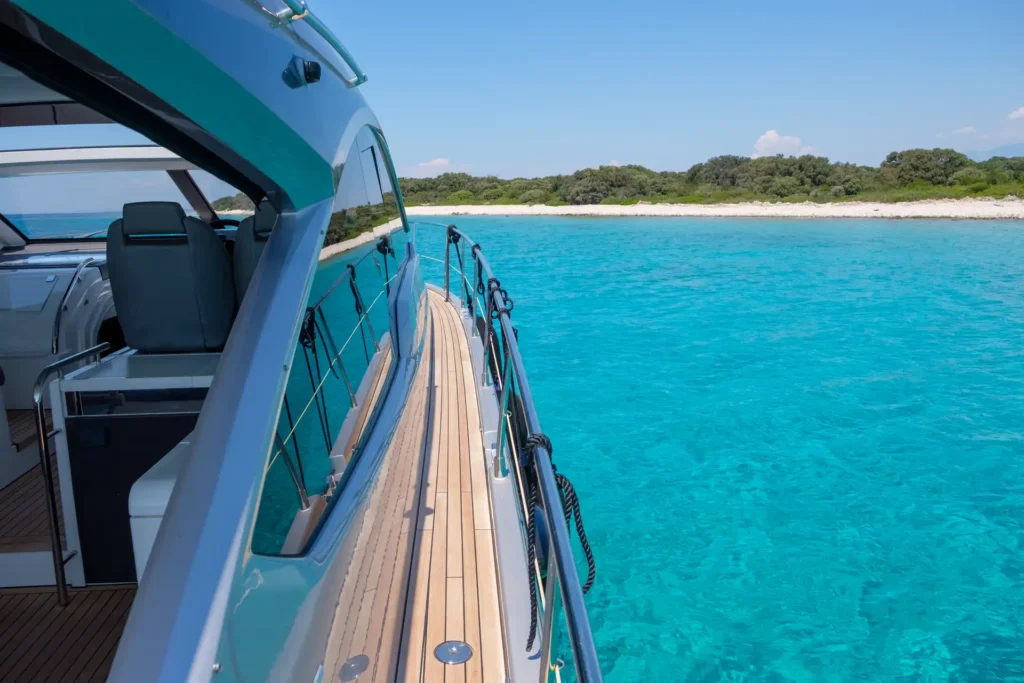 Seitlicher Gang an Bord der Fairline Targa 48 Open, Blick aufs türkisblaue Wasser und die Küste.