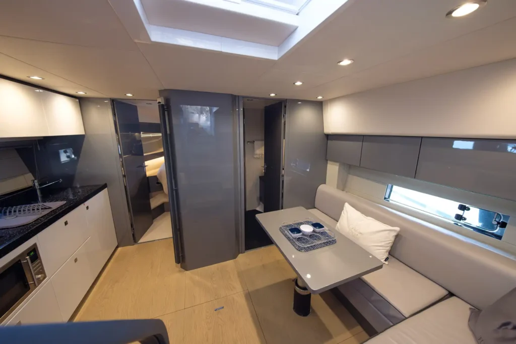 Moderner Salonbereich der Fairline Targa 48 Open mit Sitzecke, Esstisch und Blick auf Kabine und Bad.