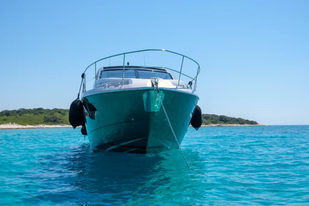 Frontale Ansicht der Fairline Targa 48 Open, die vor Anker liegt, mit sichtbarer Ankerkette und klarer Wasseroberfläche.