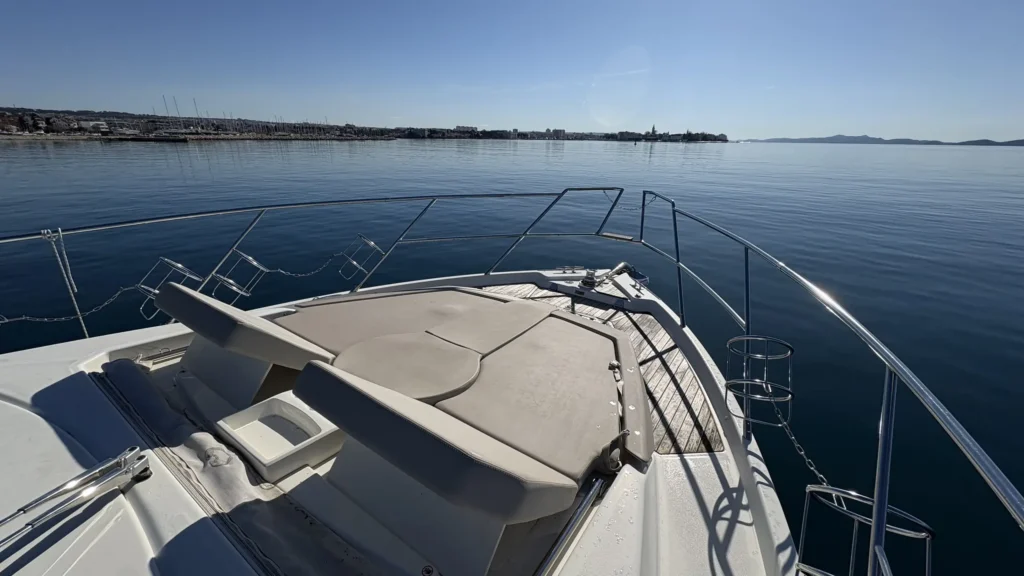 Bug-Sonnenpolster der Cranchi M44 mit Reling und weiter Aussicht auf Meer und Küste.