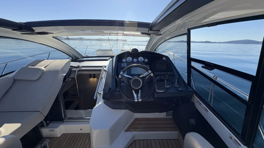 Steuerstand der Cranchi M44 mit Lenkrad und Instrumenten, links der Abgang in den Innenraum, Blick aufs Meer.