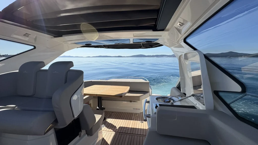 Salon der Cranchi M44 mit U-förmiger Sitzgruppe, Tisch, Oberlicht und runden Bullaugen.