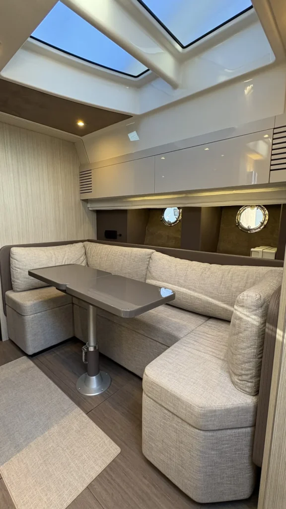 Salon der Cranchi M44 mit U-förmiger Sitzgruppe, Tisch, Oberlicht und runden Bullaugen.