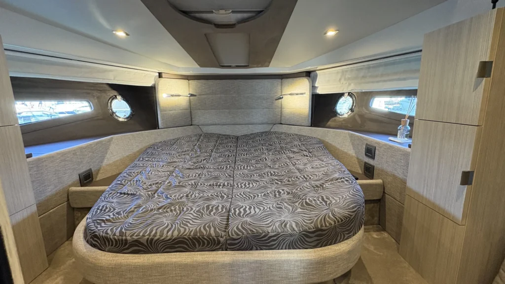 Eignerkabine der Cranchi M44 mit großem Doppelbett, seitlichen Fenstern und Bullaugen, indirekte Beleuchtung am Kopfteil.