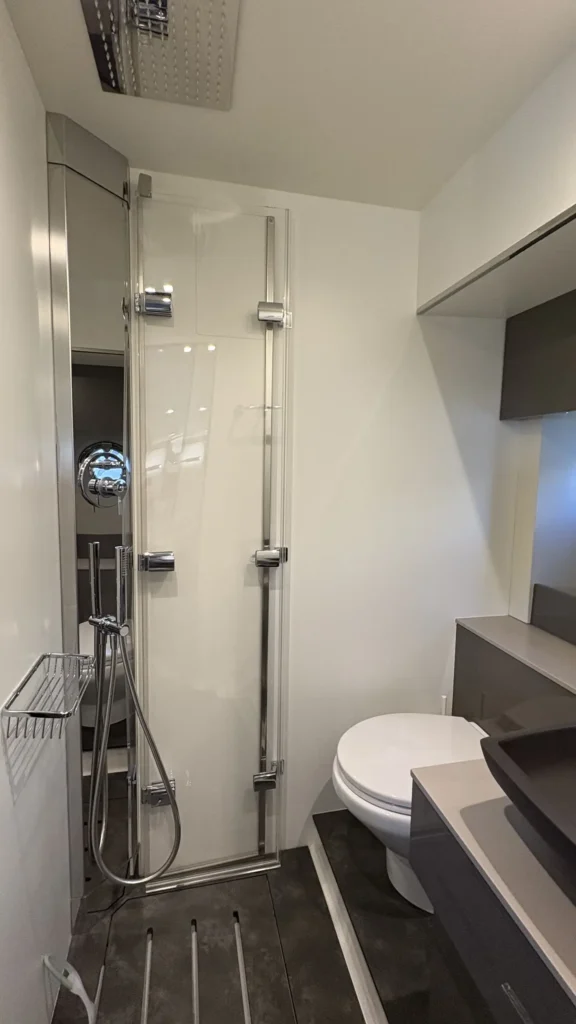 Bad der Cranchi M44 mit Duschkabine und Regendusche, WC und Waschtisch, helles modernes Layout.